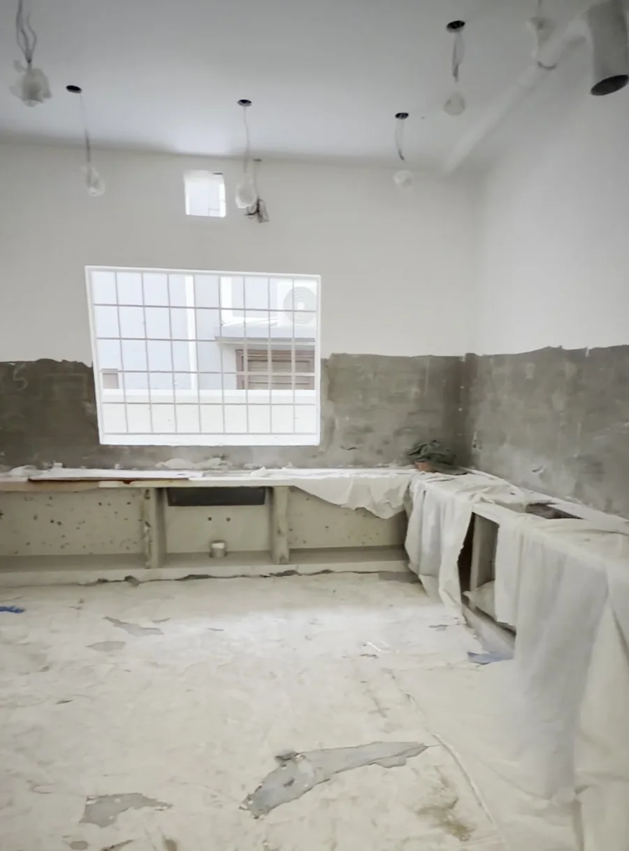 Room with bare grey plaster walls and covered counters before painting